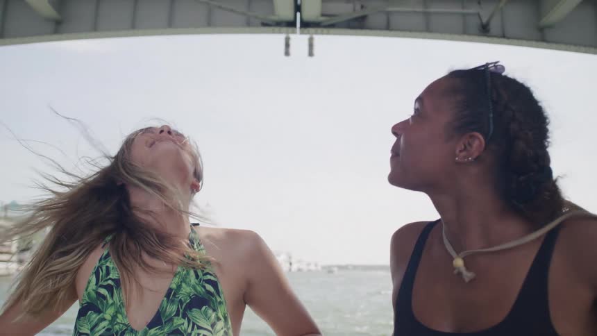 Two women smiling on a boat passing under a bridge