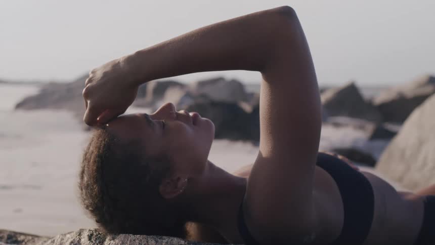 Woman lying on a beach with her arm resting over her face