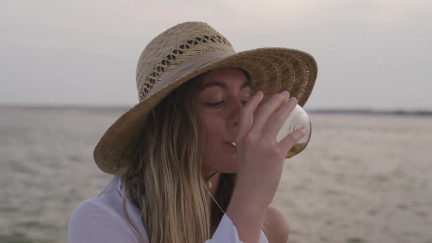 Woman enjoys a drink at the beach