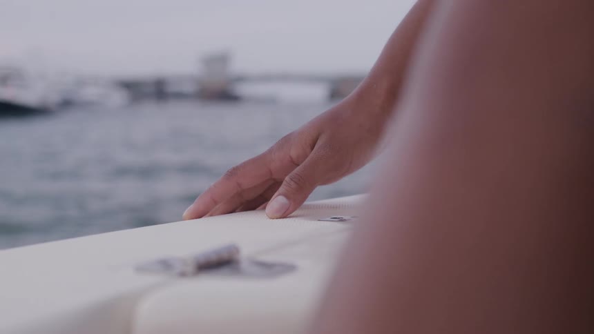 Hand rests on the edge of a moving boat at sea