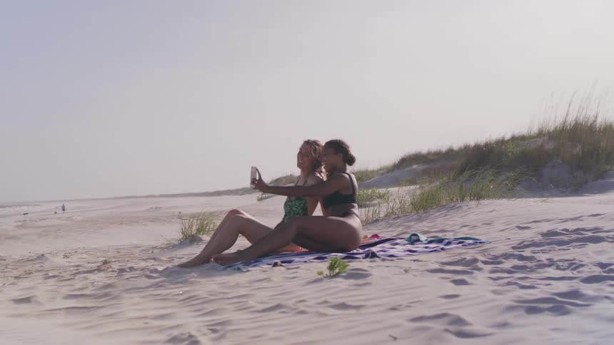 Two female friends take a selfie on the beach