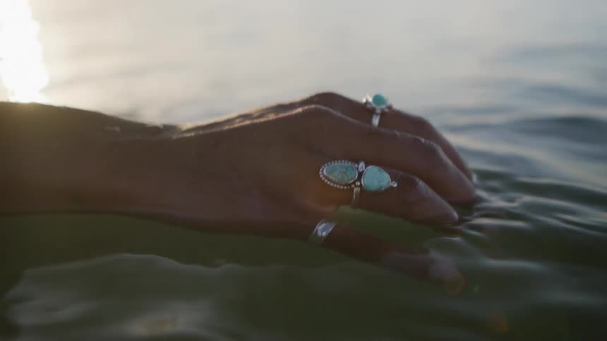 Female hand with stone rings in sea water
