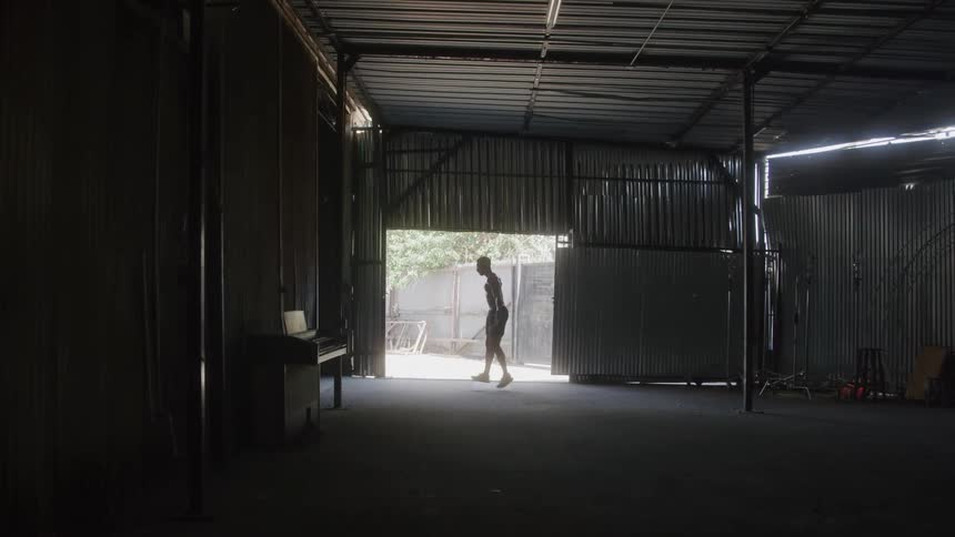 Person jumps rope inside a metal shed illuminated by external light