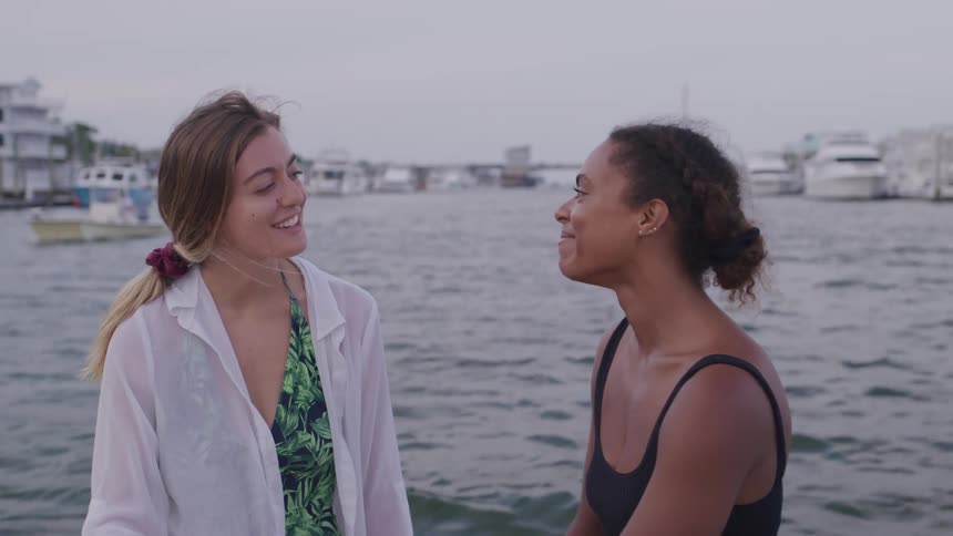 Portrait of two young women conversing outdoors on a boat at sea during daytime