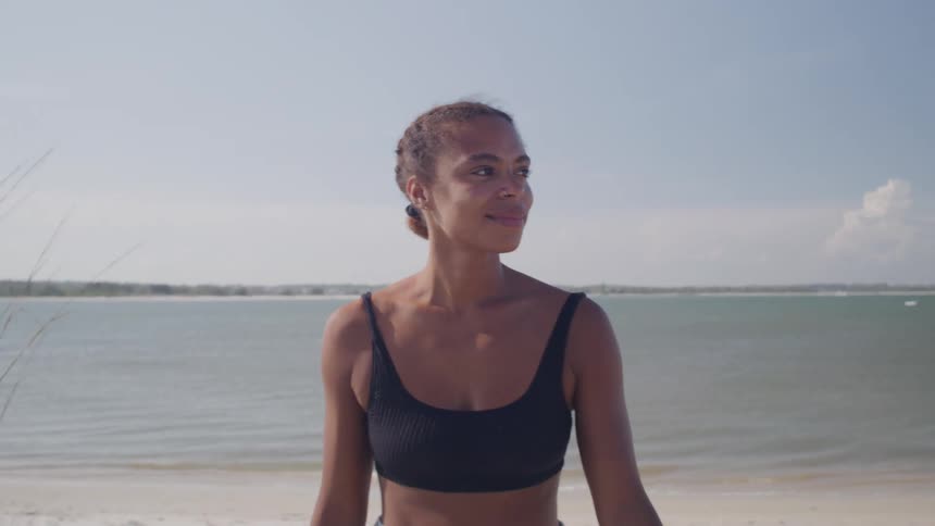 Smiling woman walks joyfully along a sunny beach