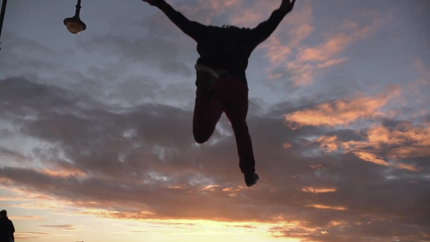 A person running and jumping high into a cloudy sky at sunset