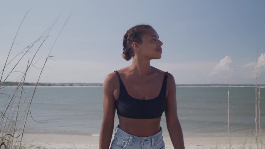 Woman in a black top and jeans smiles while enjoying the ocean view