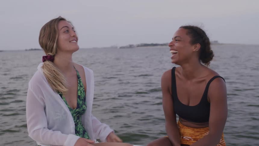 Two women sit on a boat in the ocean talking and laughing having a good time at midday