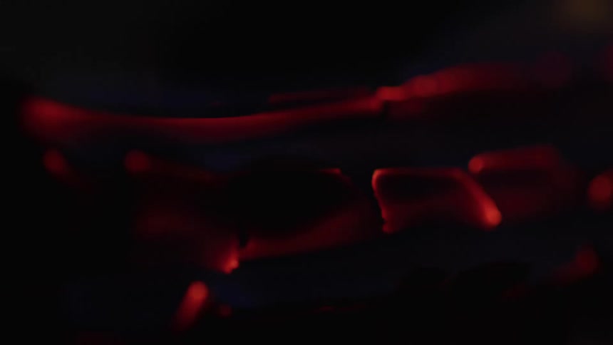 Glowing embers shine in reddish tones under low light