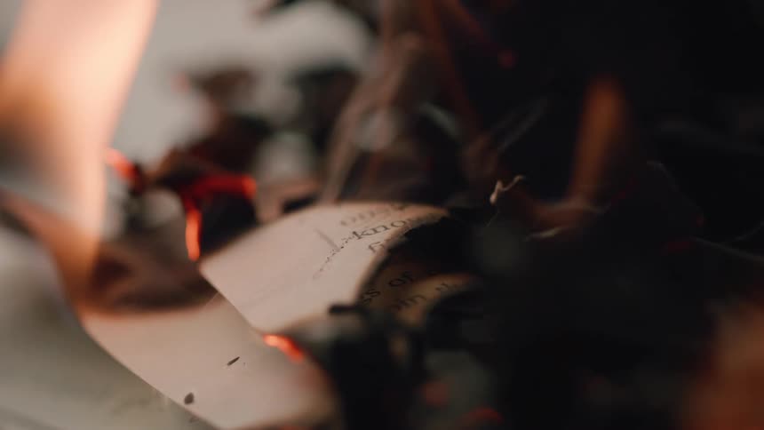 Partially burned sheets of paper with glowing embers on the edges
