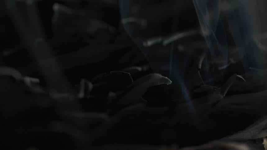 Smoke continuously rises from a layer of charred material