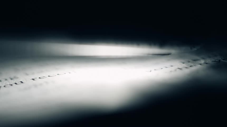 A spotlight highlights fine printed text on a dark surface creating a dramatic and mysterious atmosphere