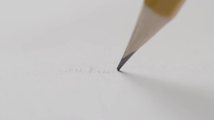 Close up of a yellow pencil writing cursive on white paper