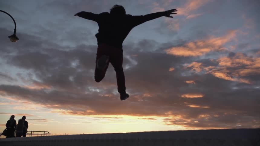 The silhouette of a person running and then leaping at sunset
