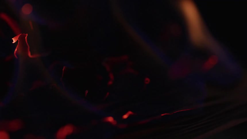 A closeup of glowing embers and flickering flames captures the heat and motion of a slow burn