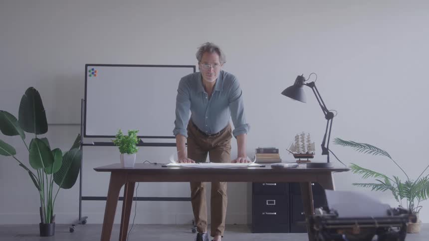A man leans over a desk in a modern office setting