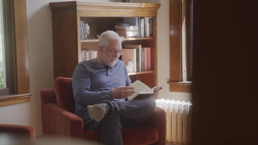 Man reads a book with a smile in a cozy indoor living area