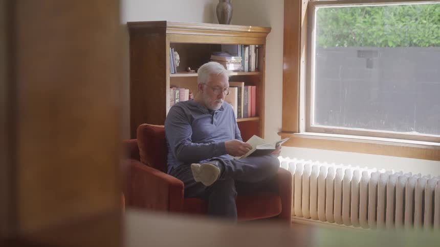 Man sitting in an armchair reading a book