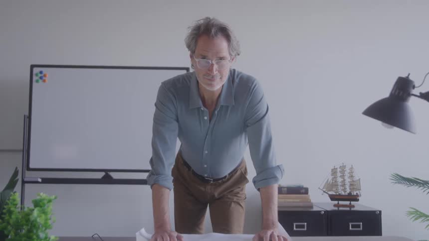 Man with glasses rests his hands on the lighted table analyzing a project