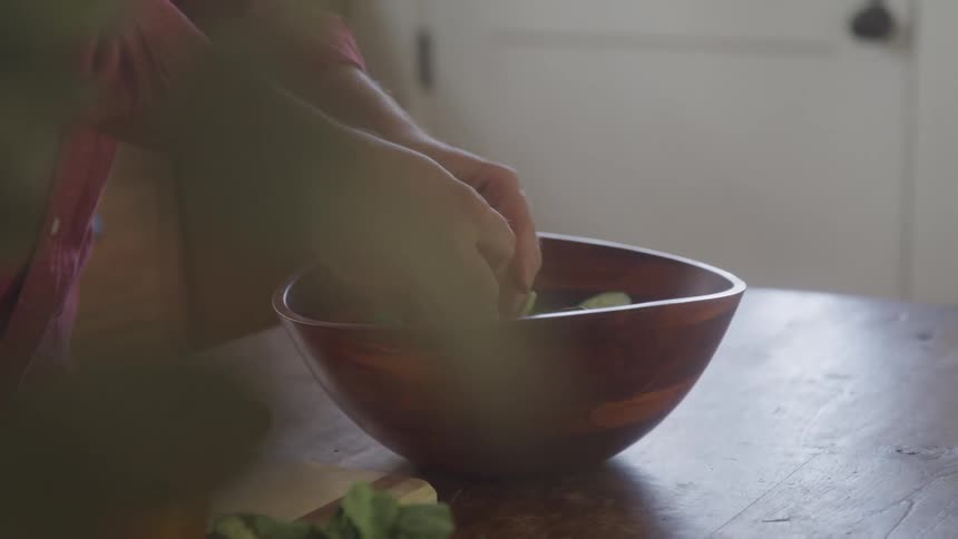 A person is preparing salad in a bowl