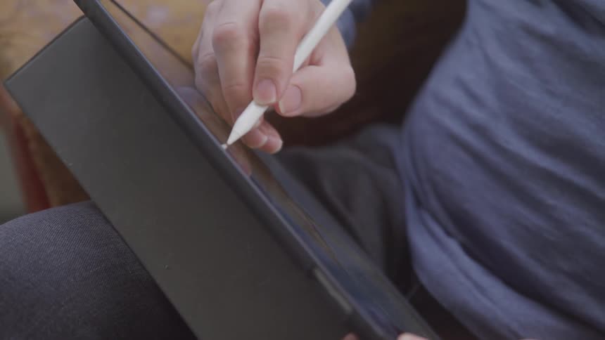 A closeup shot of a persons hand using a stylus to write or draw on a tablet device highlighting the precision and detail of the digital interaction