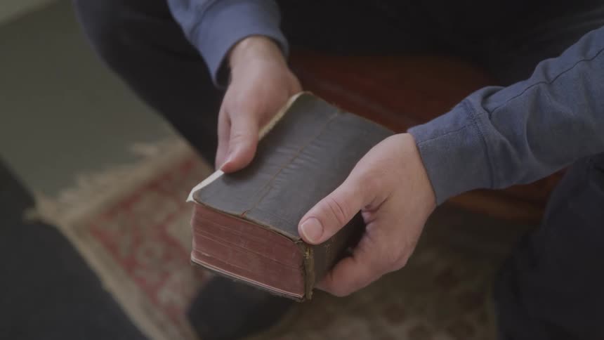 The video shows a person with a book in their hands turning the pages the book is old and has a dark worn cover