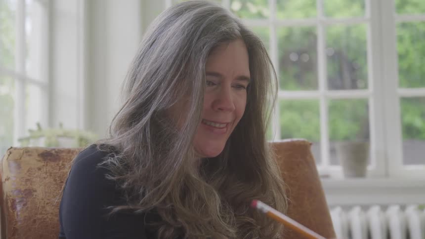 Happy woman sitting in an armchair holding a pencil