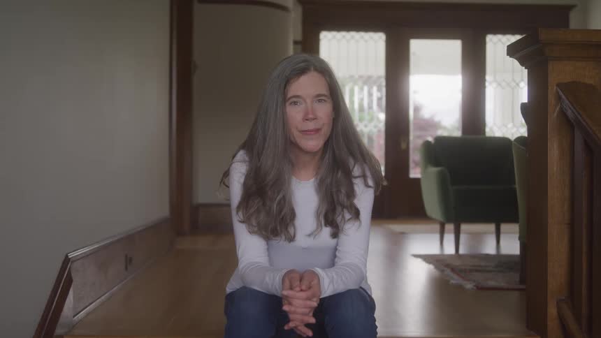Woman sitting indoors with happy expression