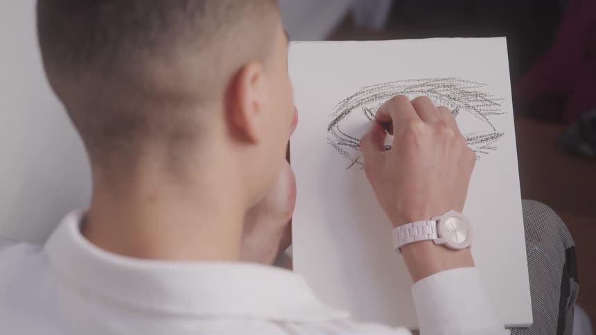 Man draws an eye on a sheet of paper using a pencil