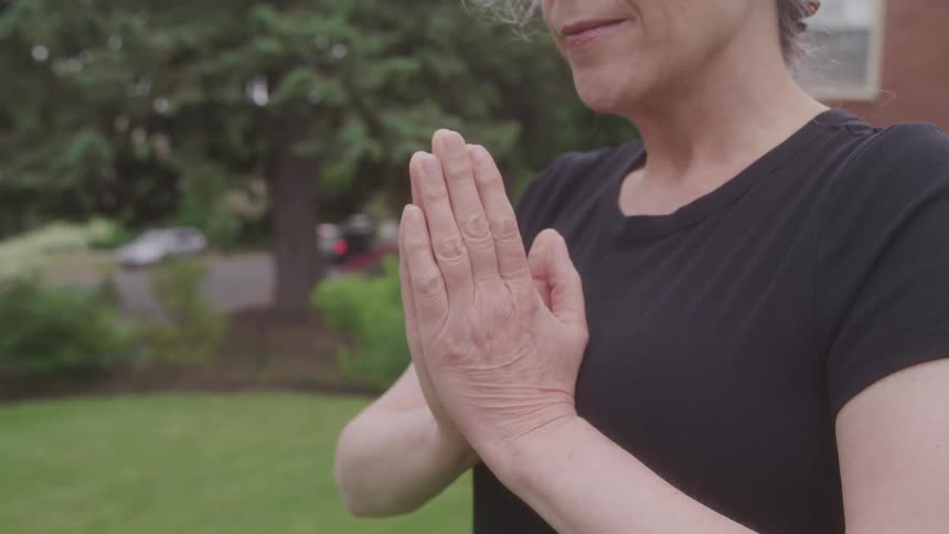 Woman outdoors brings hands together in meditation pose