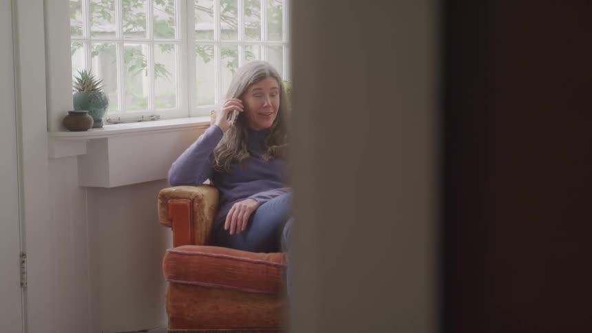 A woman sitting in an armchair talking on the phone