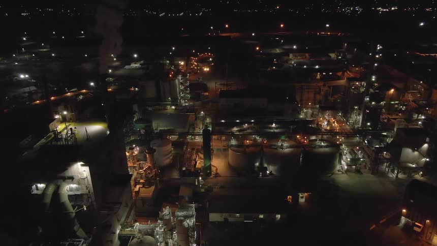 Industrial complex lit up at night with multiple structures and tanks