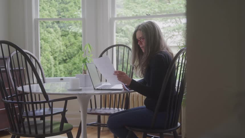 A woman uses a laptop at a round table in a cafe