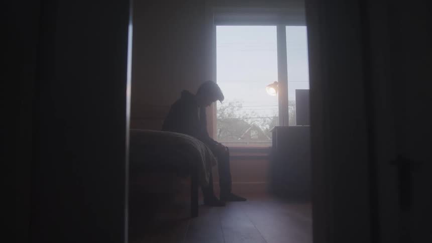 Teenager sitting on a bed in a bedroom
