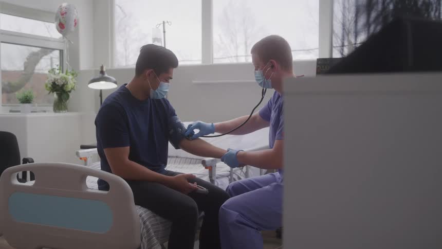 Healthcare professional checks a mans vital signs in a hospital room