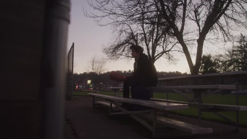 Boy sitting in the bleachers with a baseball glove