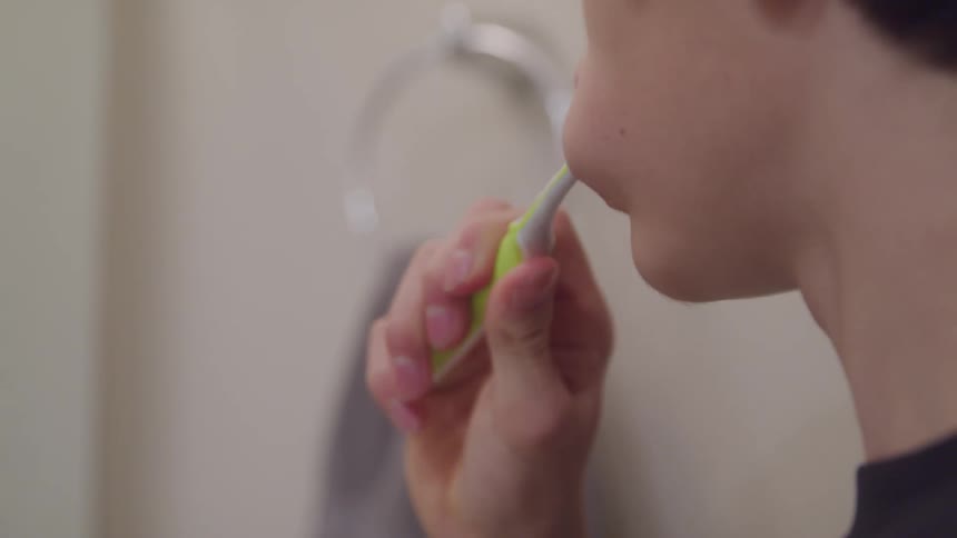 A young boy is brushing his teeth in a bathroom