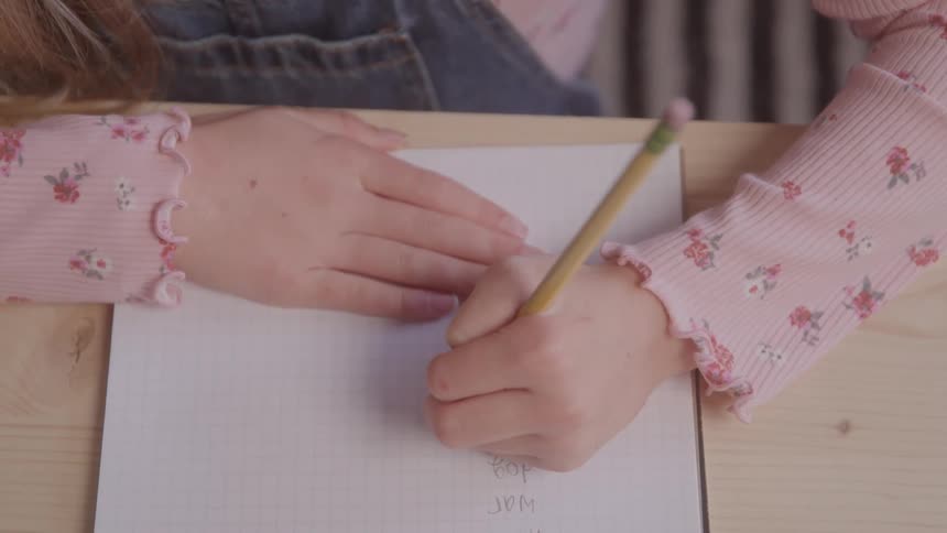 A child writes in a notebook with a pencil