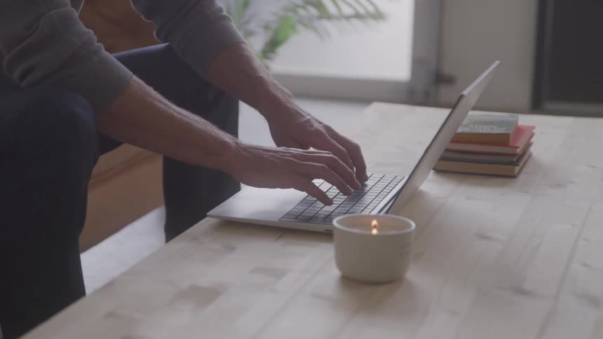A person types on a laptop while working indoors
