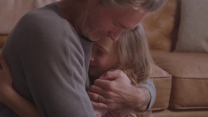 Man and girl smiling as they hug while sitting