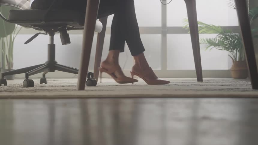 Legs of a woman in high heels on a carpet in a room