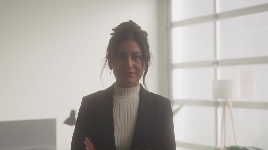 Woman in a dark suit and light blouse looks forward in a bright setting