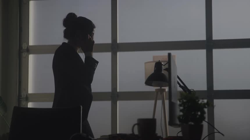 Woman walking through an office environment and talking on her cell phone on a call