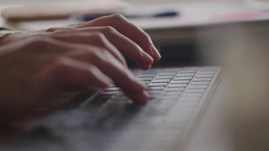Closeup of hands typing on a laptop in soft indoor light