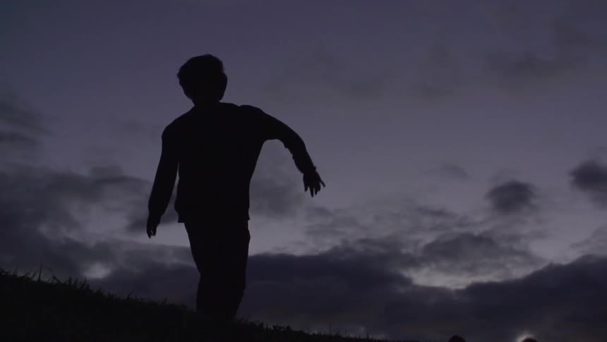 Person dancing outdoors after sunset