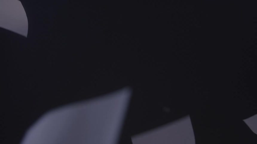 Several white sheets of paper are drifting through a dark space