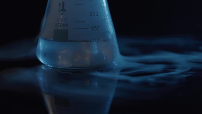 Beaker with transparent liquid rests on a reflective surface