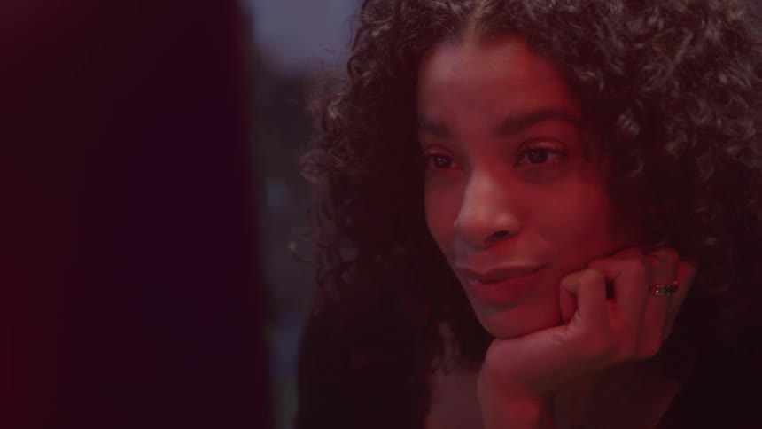 Woman with curly hair and a happy expression sitting in front of a screen
