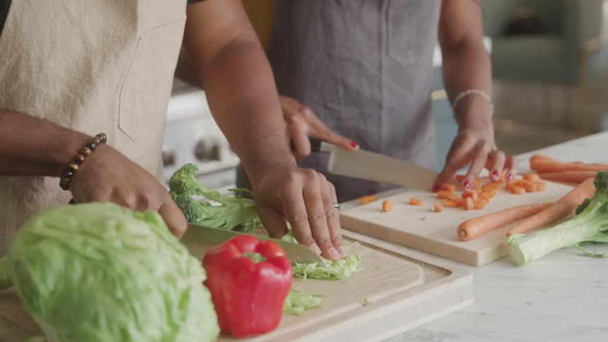 Two women are chopping vegetables at a kitchen counter