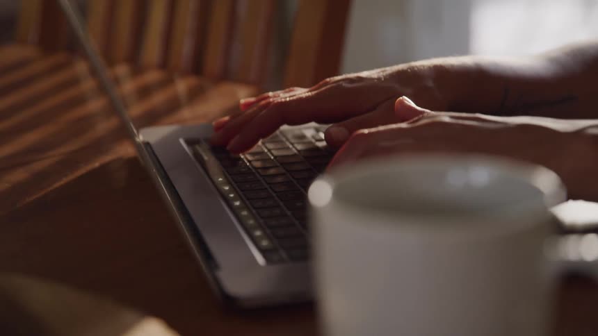 Woman sitting at home types on a laptop